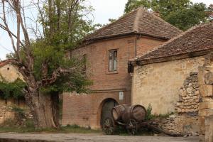 an old brick building with a barrel next to a tree at "Pivnica i smestaj Jovanovic"- Rogljevacke pivnice in Rogljevo
