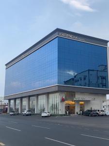 een groot glazen gebouw met auto's geparkeerd voor het bij Golden Dream Hotel in Khamis Mushayt