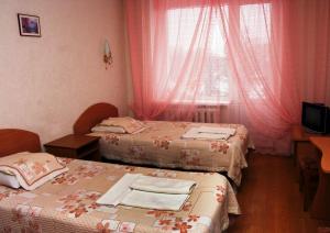 Habitación con 2 camas y ventana con cortinas rosas. en Kyiv Hotel, en Poltava