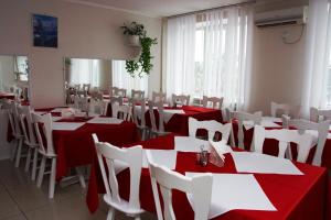 a restaurant with red and white tables and white chairs at Kyiv Hotel in Poltava