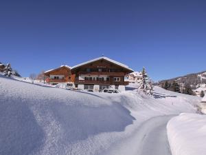 a snow covered road in front of a house at Garni Martlhof in Selva di Val Gardena