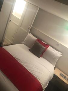 Bett mit roten und weißen Kissen in einem Zimmer in der Unterkunft Kirubash Central Pier Hotel in Blackpool