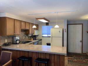 a kitchen with a white refrigerator and wooden cabinets at Beaver Village Apartment in Winter Park