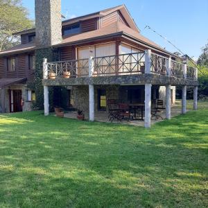 ein großes Haus mit einer Terrasse auf einem Rasen in der Unterkunft Kwezi Cottage at The Great Rift Valley Lodge & Golf Resort Naivasha in Naivasha
