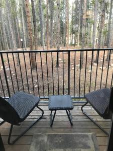 two chairs and a table on a porch with trees at Beaver Village Apartment in Winter Park