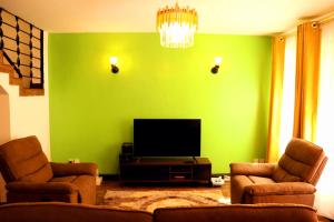 un soggiorno verde con 2 sedie e una TV a schermo piatto di Little Green Room Homestay near JKIA Airport & SGR Railway Station a Nairobi
