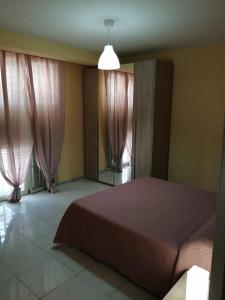 a bedroom with a bed and two windows with pink curtains at La casa del ciliegio - appartamento a Caserta in Caserta