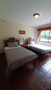 1 dormitorio con 2 camas y ventana en Kwezi Cottage at The Great Rift Valley Lodge & Golf Resort Naivasha en Naivasha