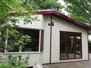 un pequeño edificio blanco con techo rojo en Roodborstje 4 persoonschalet Putten en Putten