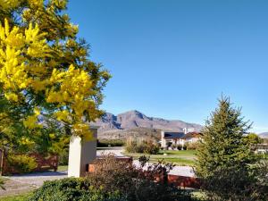 a house with a yellow tree and mountains in the background at Los Llantenes in San Andres de las Sierras