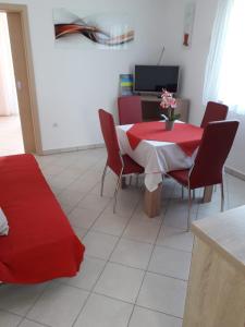 una sala da pranzo con tavolo e sedie rossi di Apartments Sandra a Rab