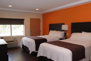 2 camas en una habitación de hotel con paredes de color naranja en Curtis Inn & Suites en Hollywood