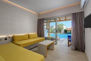 a living room with a yellow couch and a pool at Lydia Maris Resort & Spa in Kolymbia