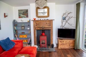 a living room with a red couch and a fireplace at Finest Retreats - Western Watch - Sea Views, Pets Accepted, Sleeps 6 in Lower Boscaswell