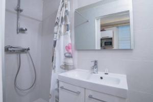 La salle de bains blanche est pourvue d'un lavabo et d'une douche. dans l'établissement Le Veyrier - Small studio for 2 people in the heart of the old town, à Annecy