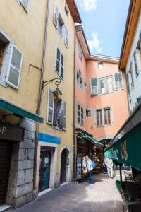 un groupe de bâtiments avec des gens qui marchent dans une rue dans l'établissement Le Veyrier - Small studio for 2 people in the heart of the old town, à Annecy