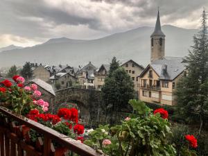 a view of a town with red flowers and a church at Vora Riu in Esterri d'Àneu