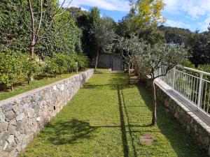 a grassy area with a fence and a stone wall at Residenza Ginepri 69 in Bergeggi