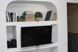 - une télévision sur une étagère blanche avec des livres dans l'établissement Prime Oceanfront Apartment 2, à Ericeira