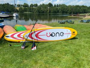 un grupo de kayaks sentados en el césped cerca de un lago en Folwark Na Półwyspie, en Nowe Worowo