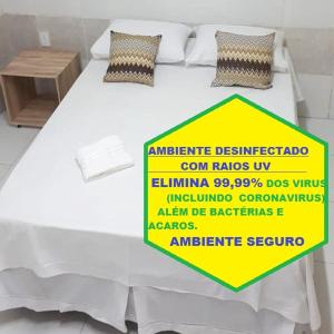 a white bed with a yellow sign on it at Pousada Pingo do Meio Dia in Mossoró