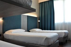 2 letti in una camera d'albergo con pareti blu di Hotel Motel Prestige a Grugliasco