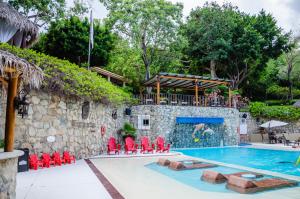 uma piscina num resort com cadeiras vermelhas e uma pessoa a nadar em Binniguenda Huatulco & Beach Club em Santa Cruz, Huatulco