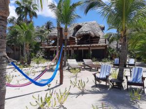 a beach area with a beach umbrella and chairs at Beach Guesthouse Holbox Apartments & Suites in Holbox Island