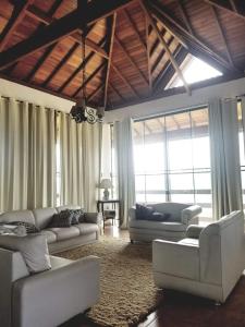 a living room with white couches and windows at Casa de vidro in São José dos Campos