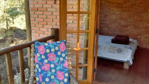 eine Veranda mit einem Bett und einer Glastür in der Unterkunft Sítio Serra do Gigante in Cruzeiro