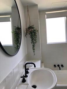 ein Badezimmer mit einem Waschbecken, einem Spiegel und einer Badewanne in der Unterkunft Le Beach Apartments in Gold Coast