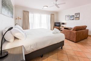 a bedroom with a large bed and a chair at Canal Rocks Beachfront Apartments in Yallingup