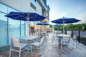 un patio avec des tables et des chaises et des parasols bleus dans l'établissement Holiday Inn Express & Suites - Lexington W - Versailles, an IHG Hotel, à Versailles