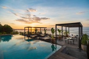 a swimming pool with tables and chairs on a building at Adiwana Warnakali Resort in Nusa Penida