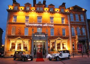 dos coches viejos estacionados frente a un edificio en Westenra Arms Hotel, en Monaghan