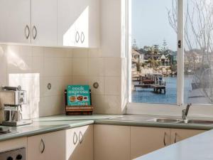 uma cozinha com um lavatório e uma janela em Waters Edge Apartment with Jetty em Mandurah