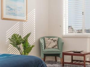 um quarto com uma cadeira verde e uma mesa em Waters Edge Apartment with Jetty em Mandurah