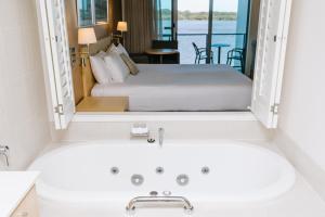 巴利纳Ramada Hotel & Suites by Wyndham Ballina Byron的一间带水槽、床和浴缸的浴室