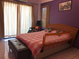 a bedroom with a bed and a chair with purple walls at David beachside apartment in Port Dickson