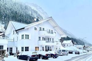 a large white building with cars parked in the snow at Apart Laresch in Ischgl