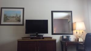 a living room with a television and a mirror at Americas Best Inn & Suites Urbana in Urbana