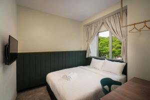 a bedroom with a bed with a window and a chair at Masson Hotel Butterworth in Perai