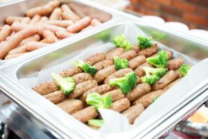 a tray of food with broccoli and sausages and hot dogs at Hotel Raffinato Sapporo in Sapporo