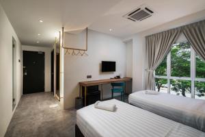 a bedroom with two beds and a desk and a television at Masson Hotel Butterworth in Perai