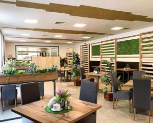 um restaurante com mesas de madeira, cadeiras e plantas em Hotel - Restauracja "SŁONECZNA" em Jarocin