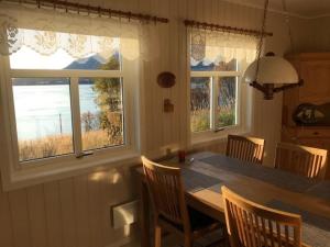 cocina con mesa, sillas y ventanas en Bustad en Larseng