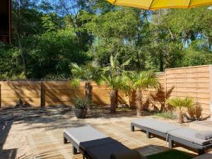 a patio with two benches and an umbrella at Blue Ocean in Moliets-et-Maa