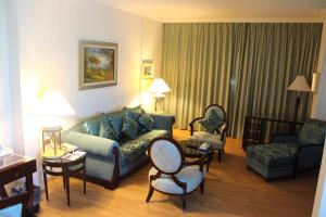 ein Wohnzimmer mit einem Sofa und Stühlen in einem Hotelzimmer in der Unterkunft Swiss Al Hamra Hotel in Dammam