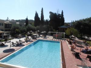 a large swimming pool with chairs and umbrellas at Frosini Gardens in Kassiopi