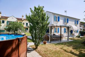 a house with a pool and a tree in the yard at Cà del Mar rustico a Jesolo con giardino e piscina privati ad uso esclusivo # in Jesolo